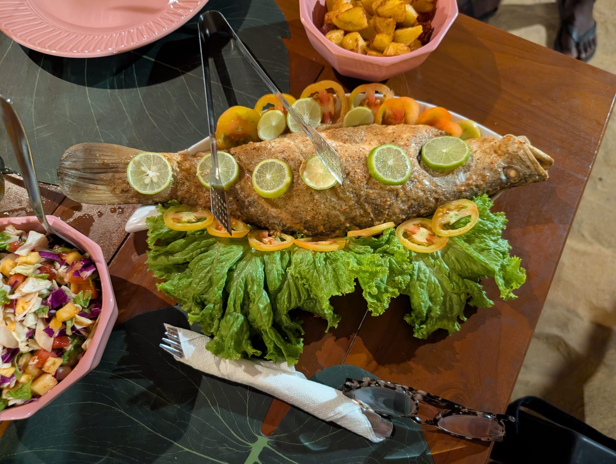 A whole grilled fish with lime, salad and potatoes