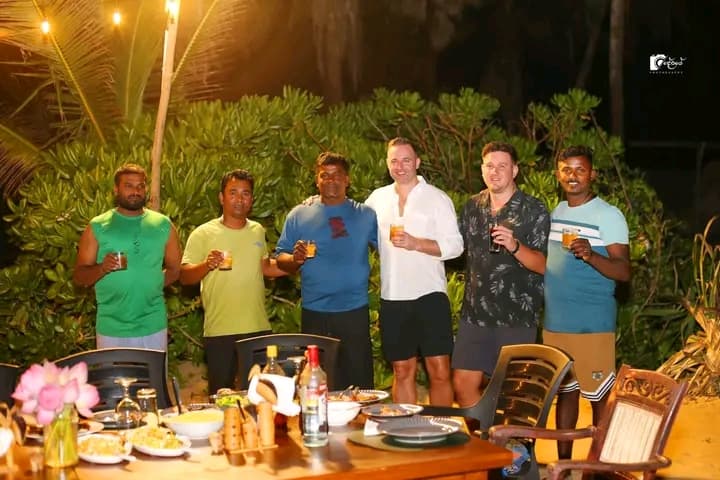 A group of guests gathered around a candlelit dinner table on the sand