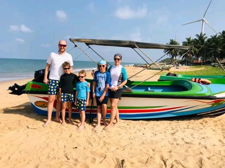 A family standing beside the boats on the beach