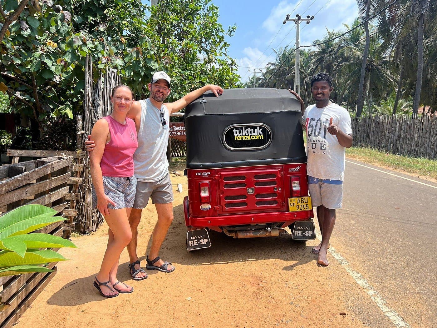 A smiling couple standing beside a tuk-tuk in Kalpitiya