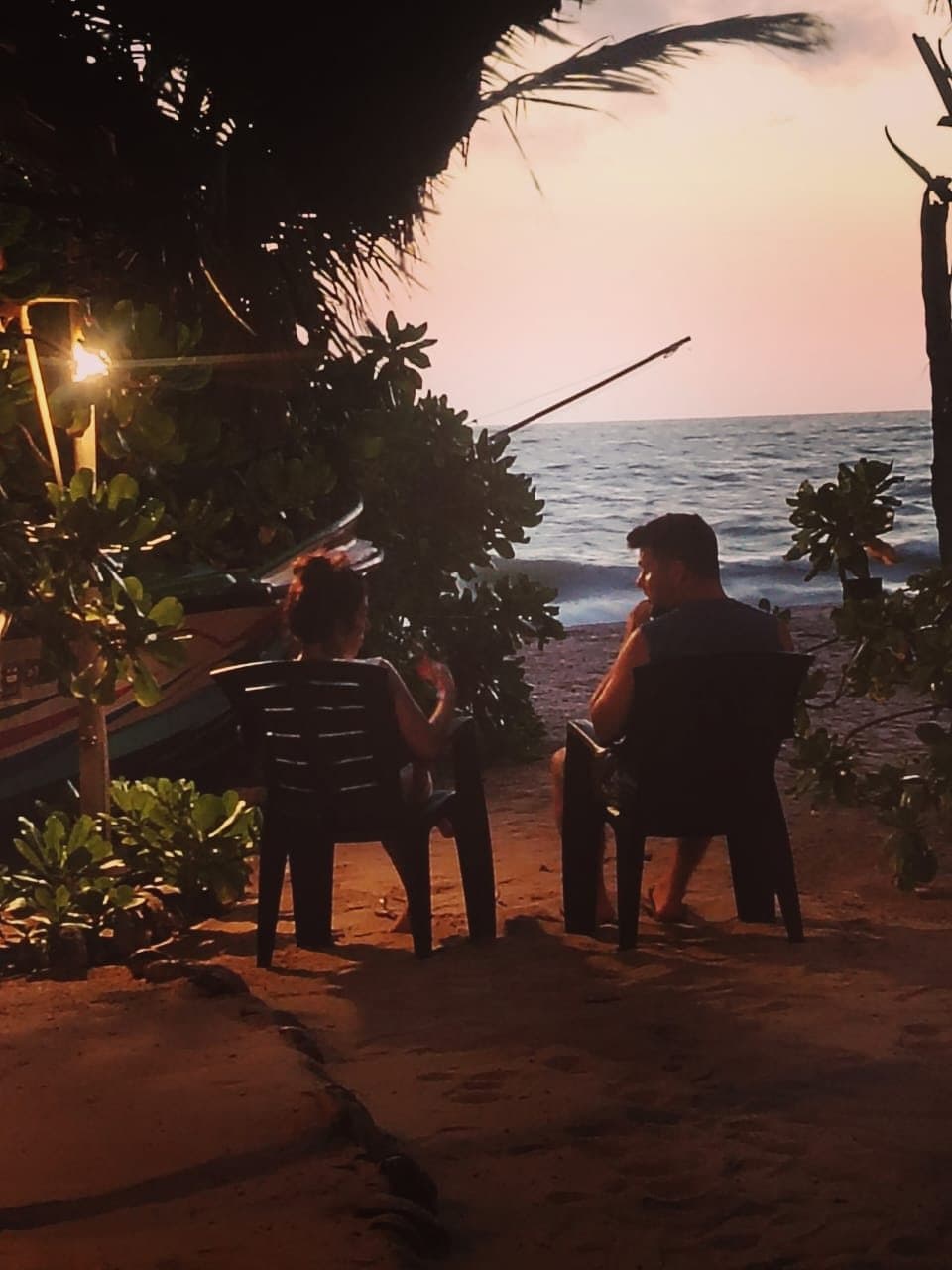Two guests silhouetted against the ocean at sunset