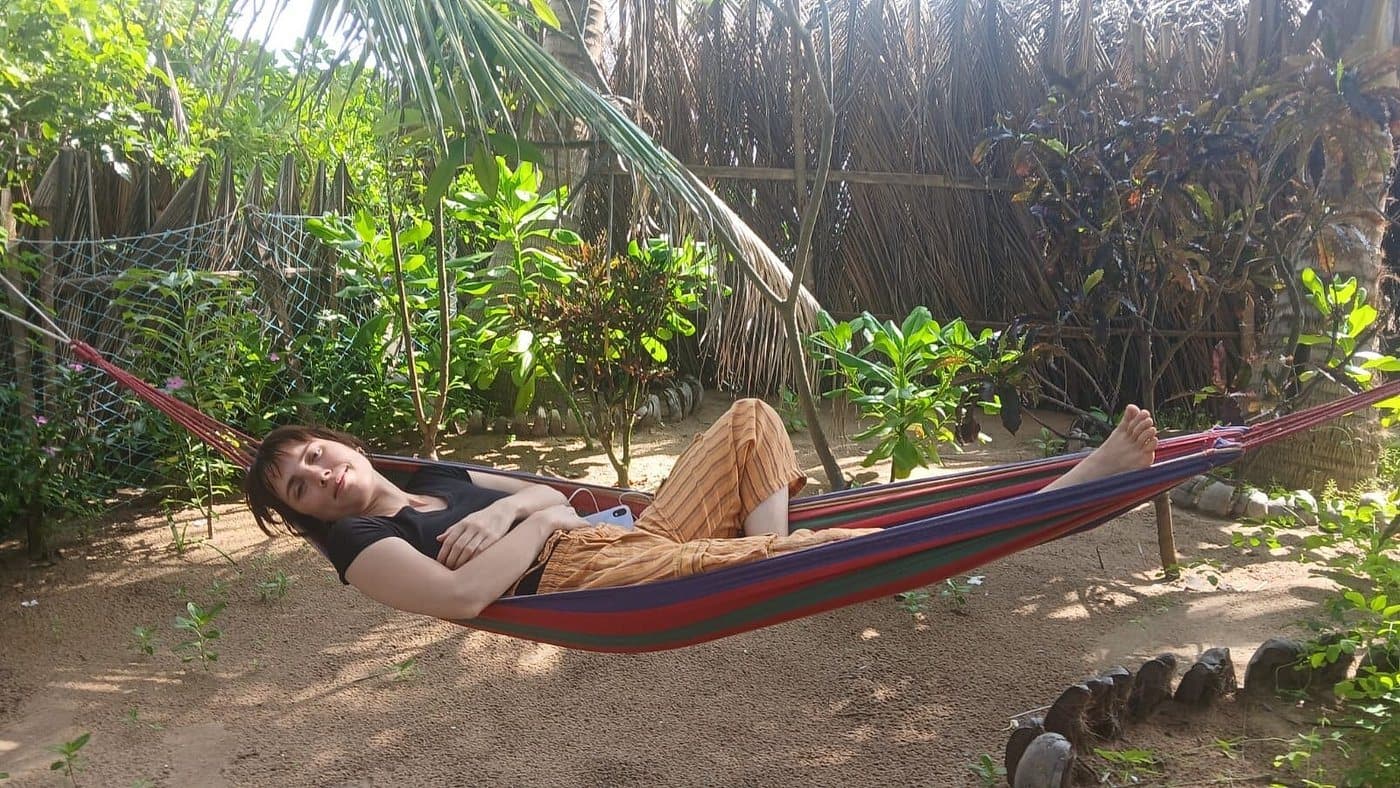 A guest relaxing in a hammock under the palms