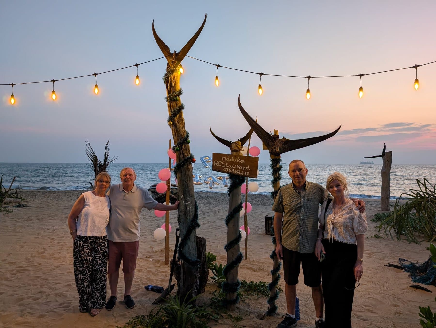 Guests gathered by the beach sign at sunset