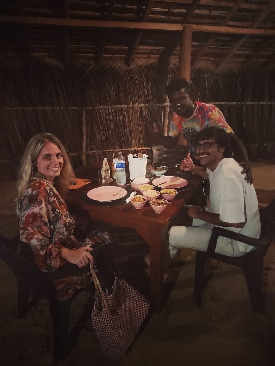 Maduka and guests at a table in the thatched restaurant
