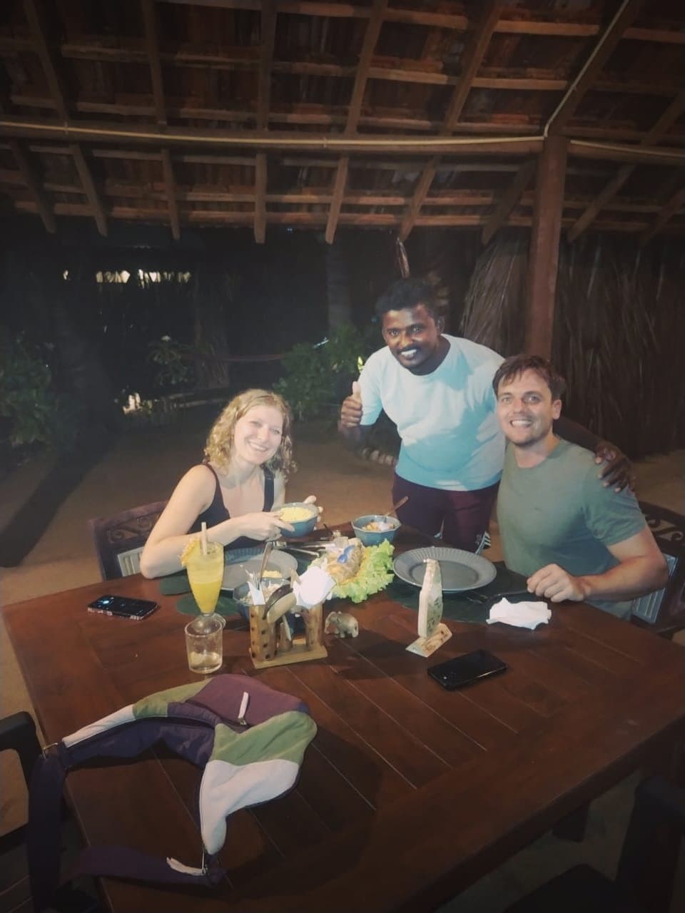 Maduka smiling with two guests at a restaurant table