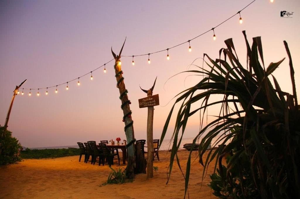 Beachfront dining tables beneath string lights at dusk