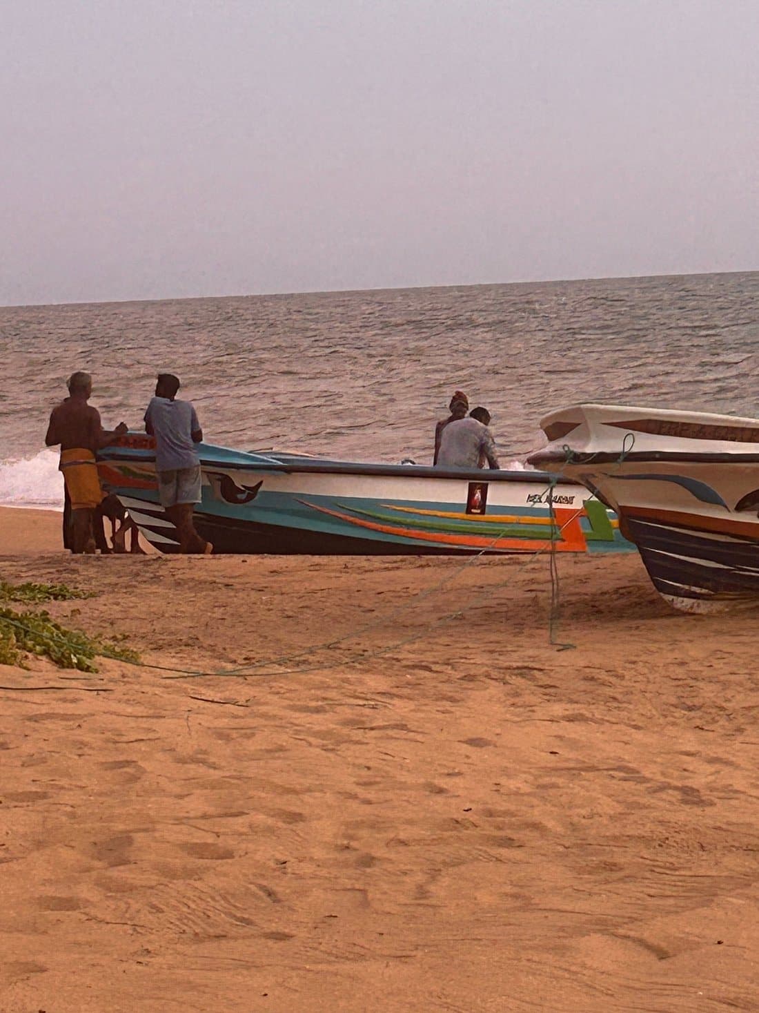 Fishermen and their boats in the shallows at dusk
