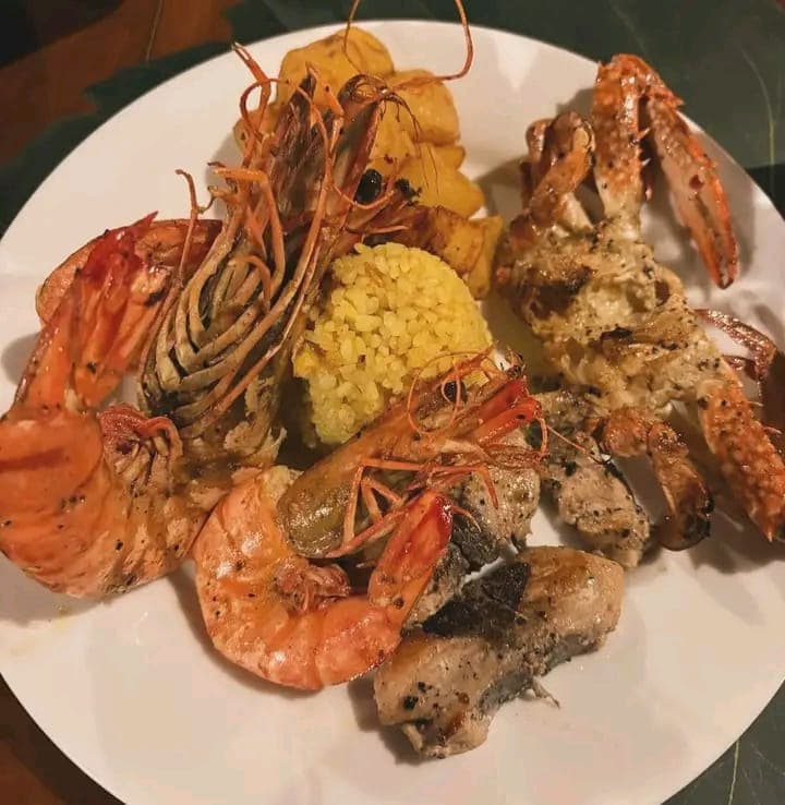 Grilled prawns, crab and fish with yellow rice and roast potatoes