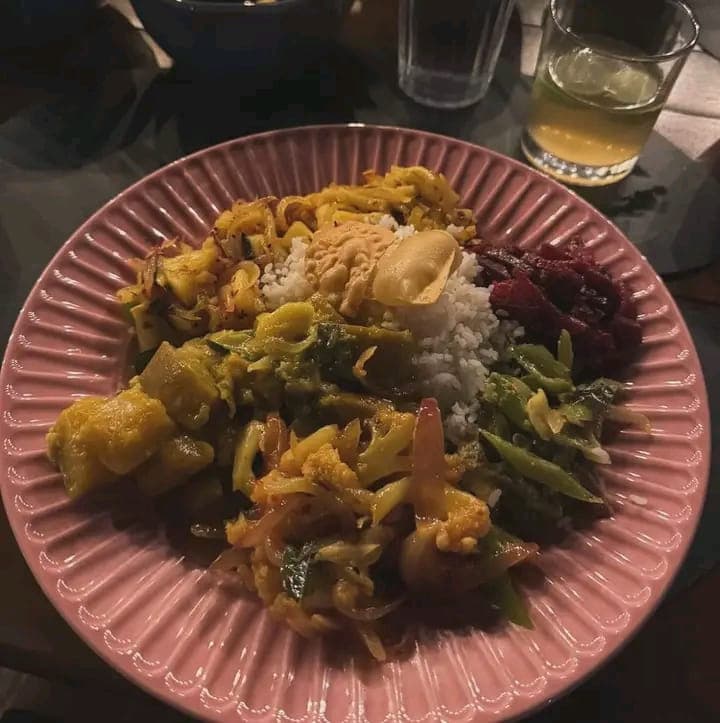 A pink plate of rice, papadum and five vegetable curries