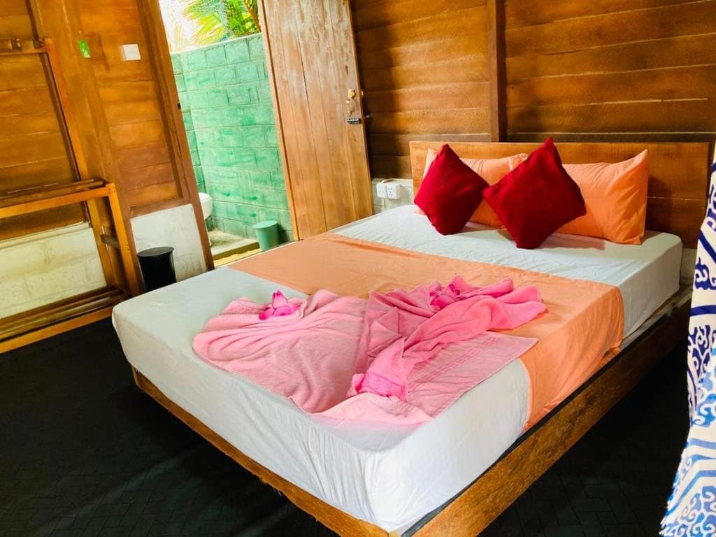 A double bed with pink and orange linen in a timber chalet